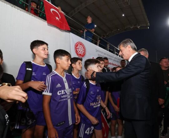 Alt text: Türk bayrağı ve sporcuların yer aldığı etkinlik.