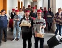 Kutlama yapan grup, ofis koridorunda, geleneksel kıyafetlerle ve gülümseyerek poz veriyor.